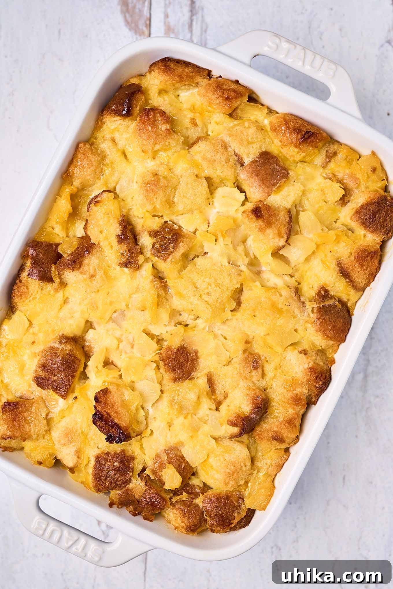 Sunshine Pineapple Bliss 6 A white oblong casserole of scalloped pineapple on a distressed white wooden surface, ready to be served.