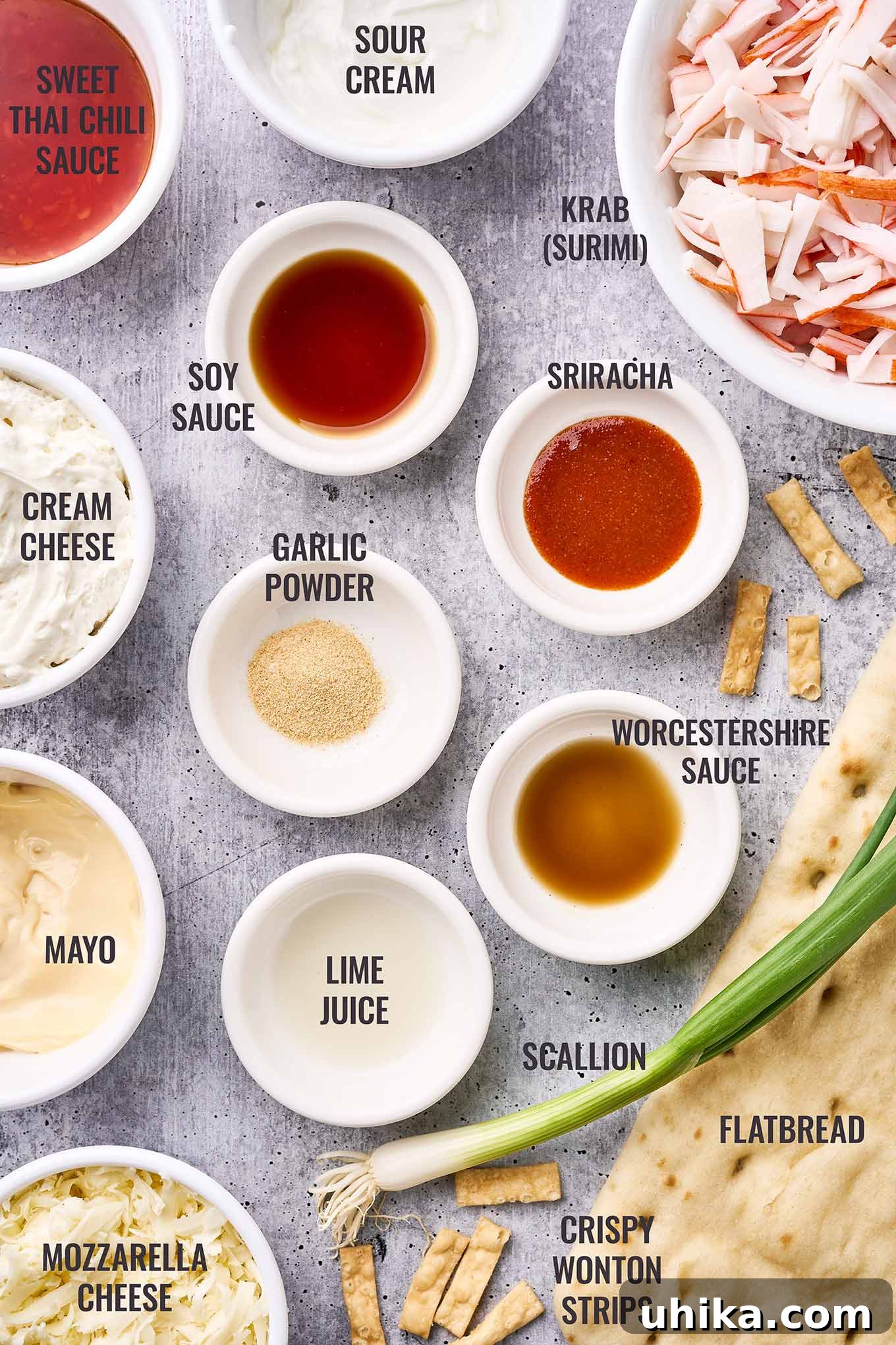 Creamy Crab Rangoon Pizza 3 A labeled, overhead view of the ingredients for crab Rangoon flatbread pizza including krab (surimi), cream cheese, sour cream, mayo, flatbread, wonton strips, and more.