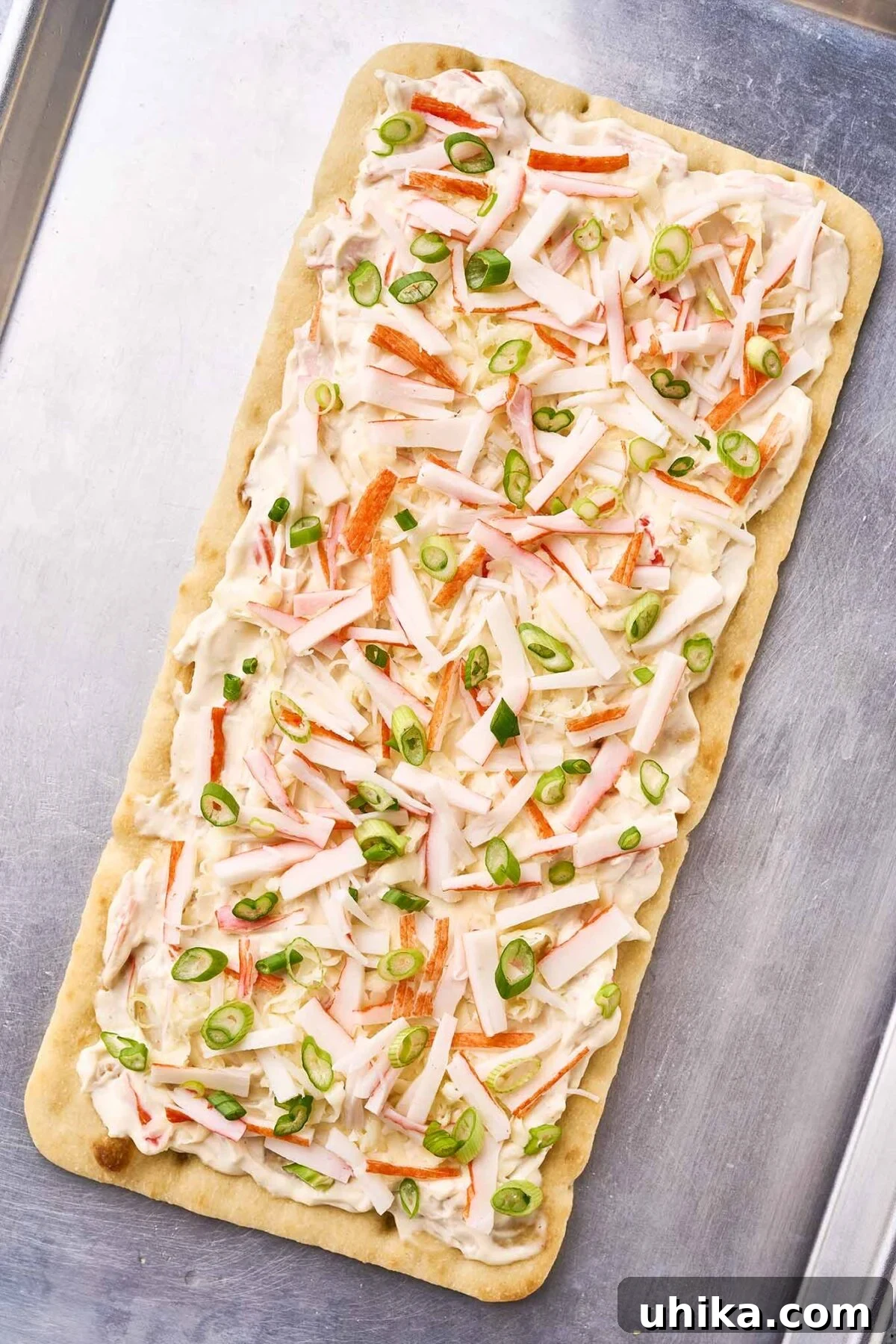 Creamy Crab Rangoon Pizza 5 A fully-assembled crab Rangoon flatbread on a baking sheet, ready for the oven.