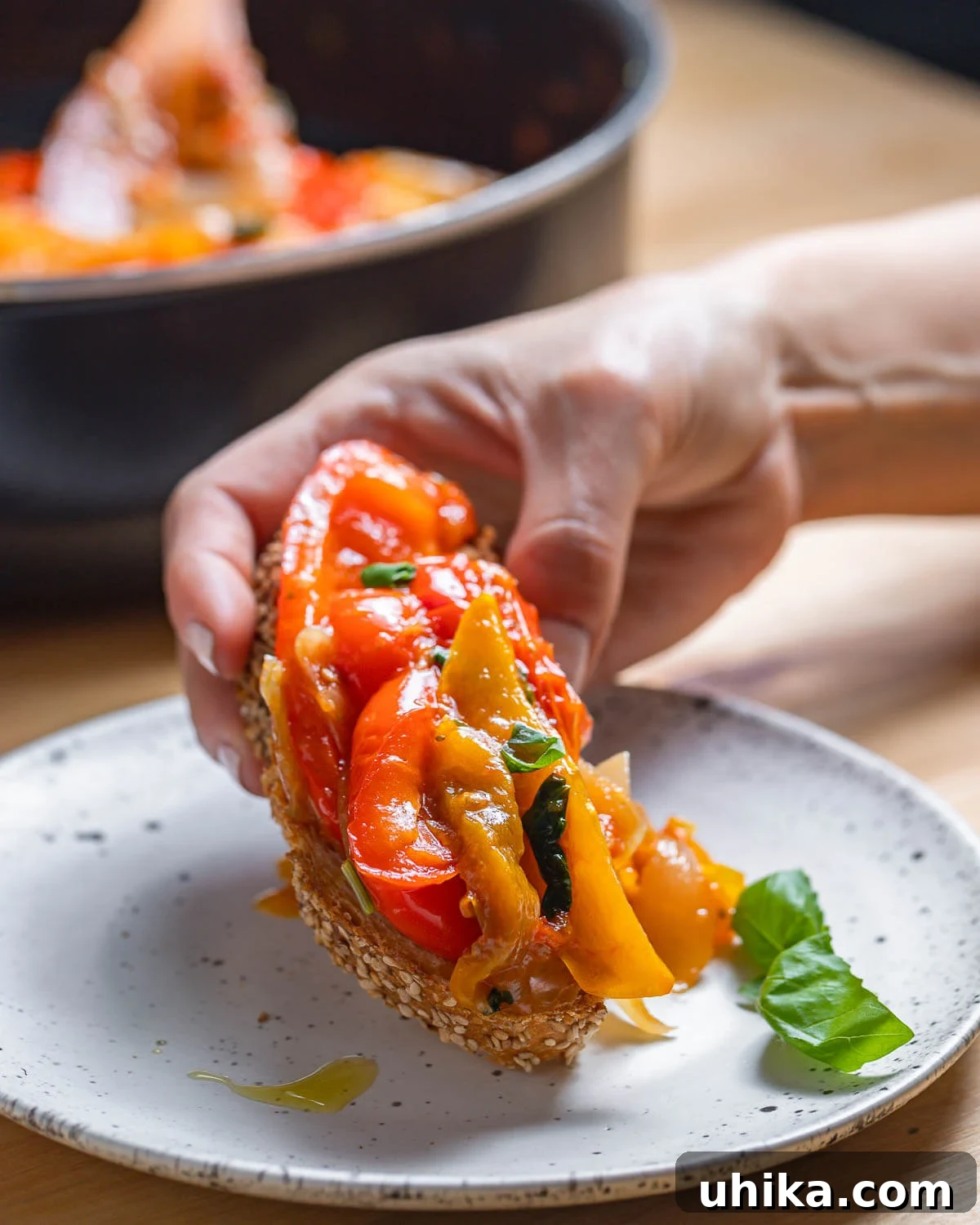 Mediterranean Pepper Delight 2 Toasted Italian bread generously topped with vibrant peperonata, held in hands over a white plate.
