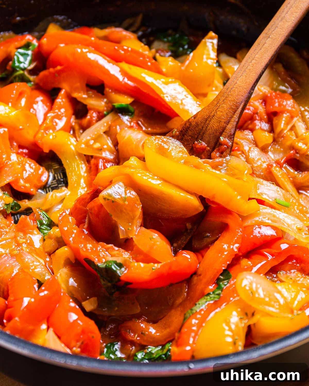 Mediterranean Pepper Delight 8 A close-up of tender peppers and onions simmering in a black pan with a wooden spoon, showcasing the rich texture before tomatoes are added.