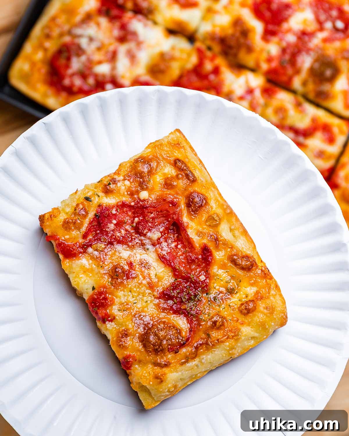 Heirloom Pan Pizza 2 Slice of Grandma pizza in white plate with full pie below.