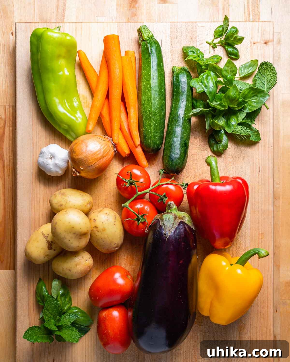 Rustic Italian Garden Stew 4 A colorful array of fresh summer vegetables laid out, including vibrant bell peppers, slender carrots, green zucchini, fragrant herbs, firm potatoes, ripe tomatoes, dark eggplant, pungent garlic, and a crisp onion, ready for Ciambotta preparation.