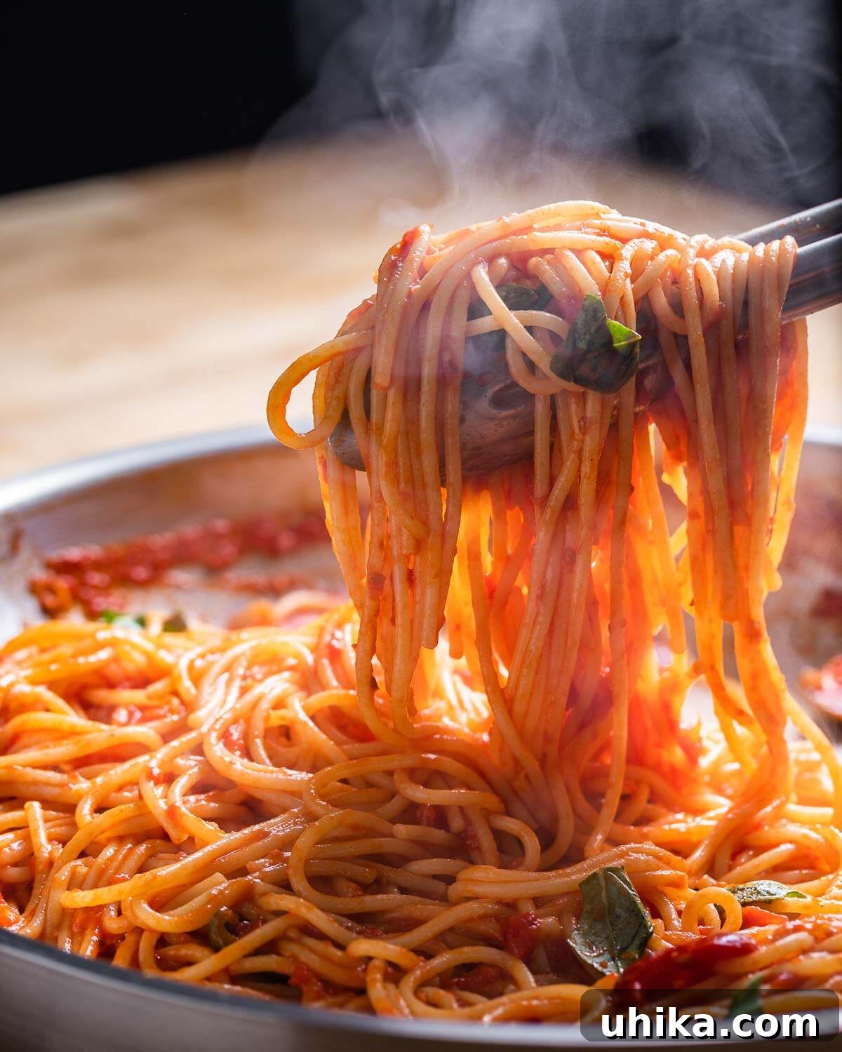 Fiery Tomato Spaghetti 6 Tongs pulling out hot spaghetti arrabbiata with steam showing.
