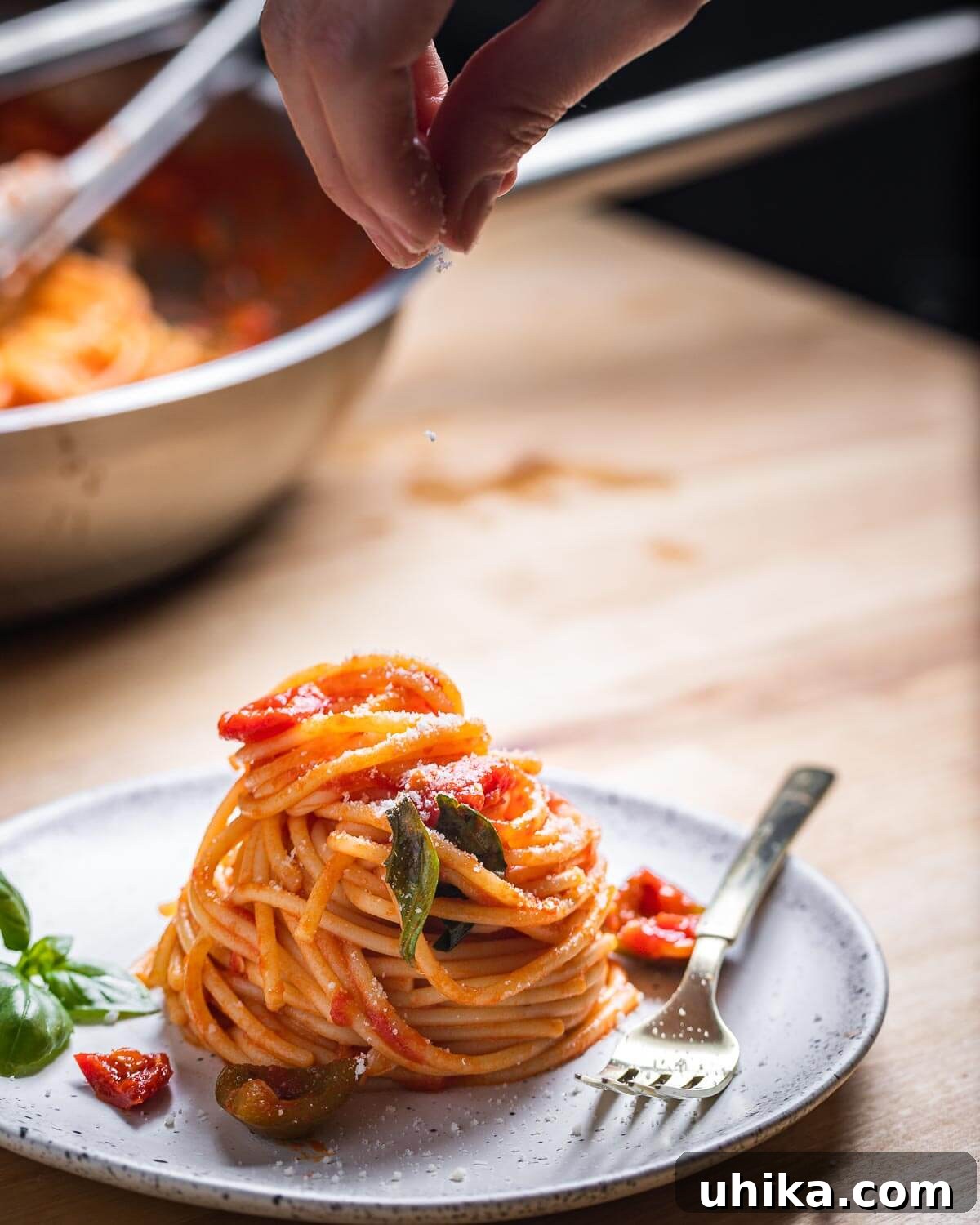 Fiery Tomato Spaghetti 8 Sprinkling cheese onto plate of spaghetti.