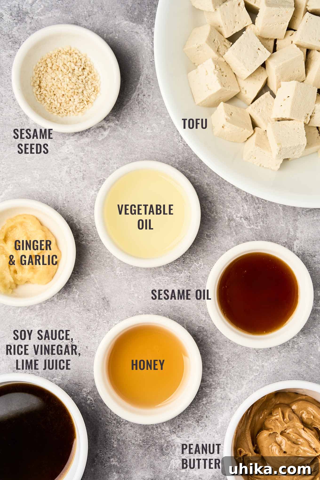 Zesty Peanut Noodle Bowl 4 A detailed overhead view of ingredients for the creamy peanut dressing and crispy tofu: creamy peanut butter, savory soy sauce, golden honey, fresh lime juice, aromatic garlic and ginger, firm tofu, and crunchy sesame seeds.