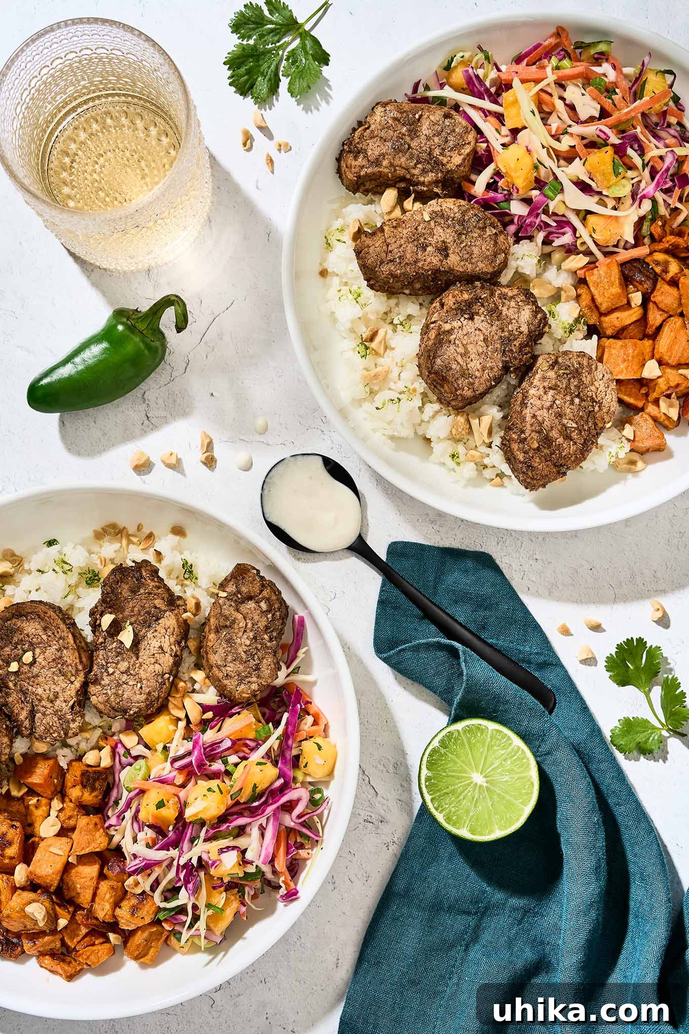 Caribbean Jerk Pork Tenderloin with Bright Garlic-Lime Drizzle 2 Jerk pork tenderloin slices served over coconut lime rice, with pineapple slaw, and roasted sweet potatoes, garlic-lime drizzle on a spoon in the center.