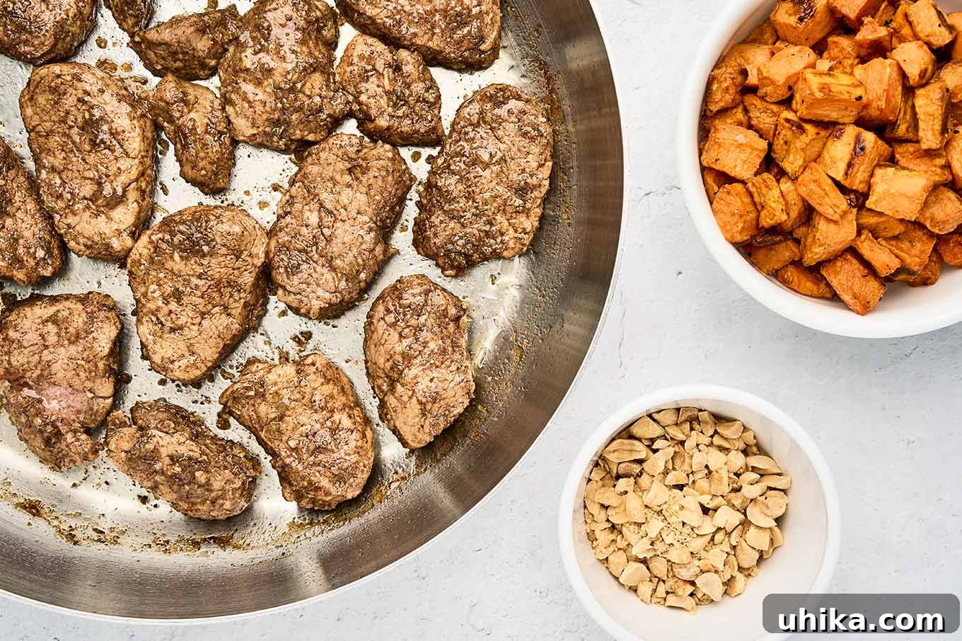 Caribbean Jerk Pork Tenderloin with Bright Garlic-Lime Drizzle 6 Seared jerk pork tenderloin medallions in a skillet, with bowls of roasted sweet potato cubes and chopped toasted peanuts alongside.