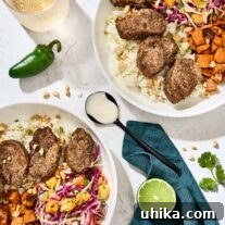 Jerk pork tenderloin slices served over coconut lime rice, with pineapple slaw, and roasted sweet potatoes, garlic-lime drizzle on a spoon in the center.