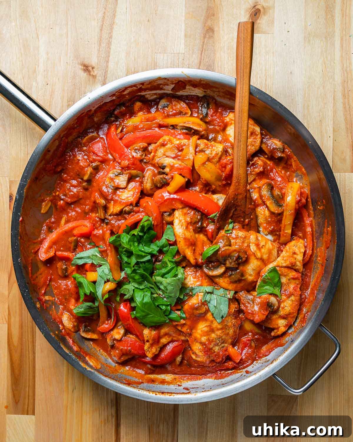 Pizzaiola Chicken 7 An overhead shot of a large pan brimming with Chicken Pizzaiola, featuring chicken pieces, bell peppers, and mushrooms submerged in a vibrant tomato sauce.