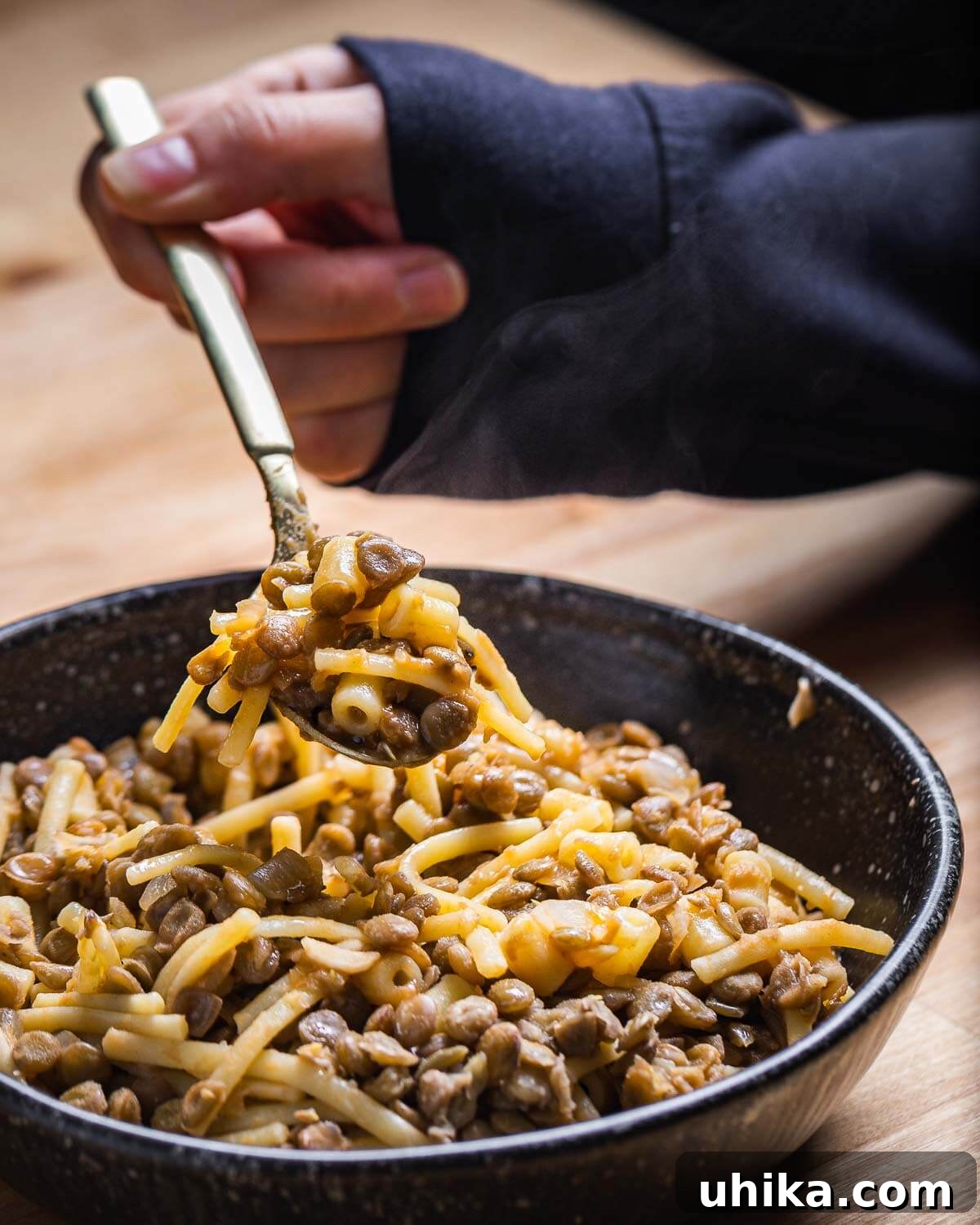 Hand holding spoonful of pasta e lenticchie.