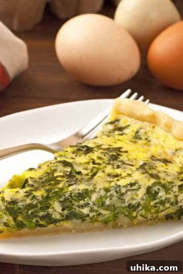 Crafting Memorable Brunch Spreads 9 A slice of spinach and cheese quiche on a plate with a fork, fresh eggs and and a tea towel in the background.