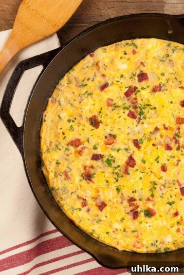 Crafting Memorable Brunch Spreads 10 An overhead view of a bacon and cheese frittata in a cast iron pan garnished with extra bacon bits and chopped parsley.