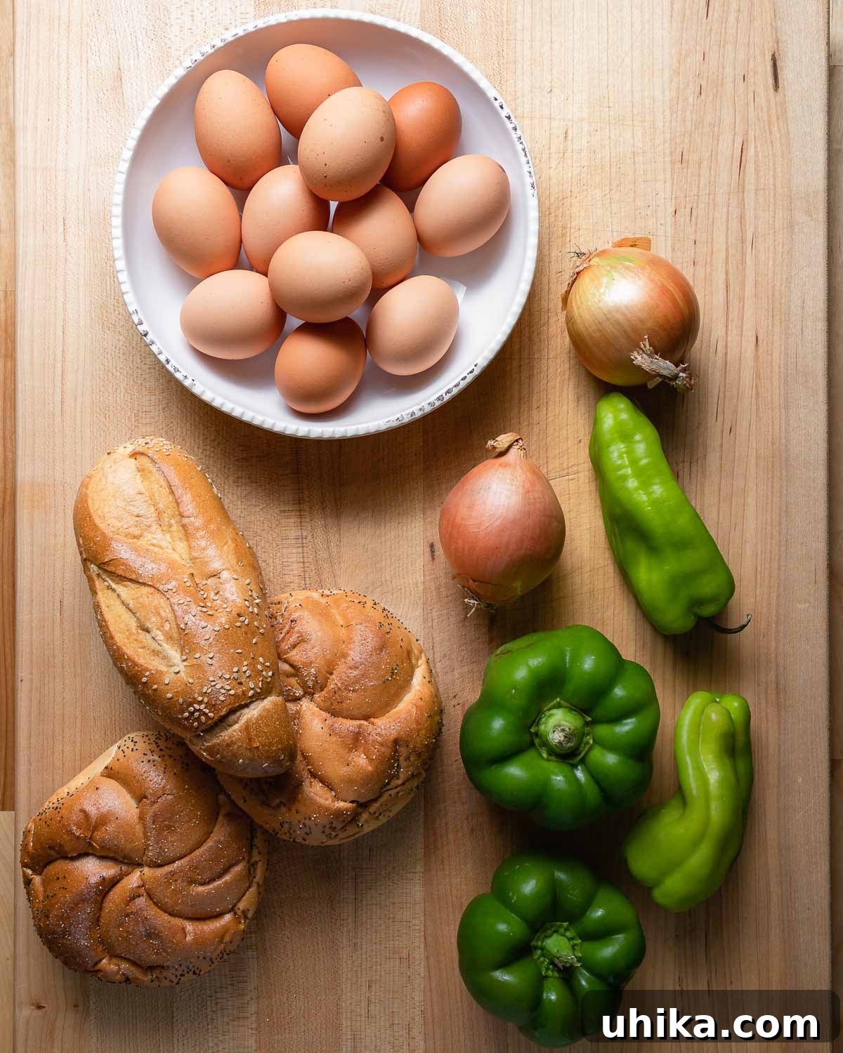 Savory Pepper & Egg Stack 4 Ingredients for pepper and egg sandwich: fresh eggs, vibrant peppers, onions, and various deli rolls.