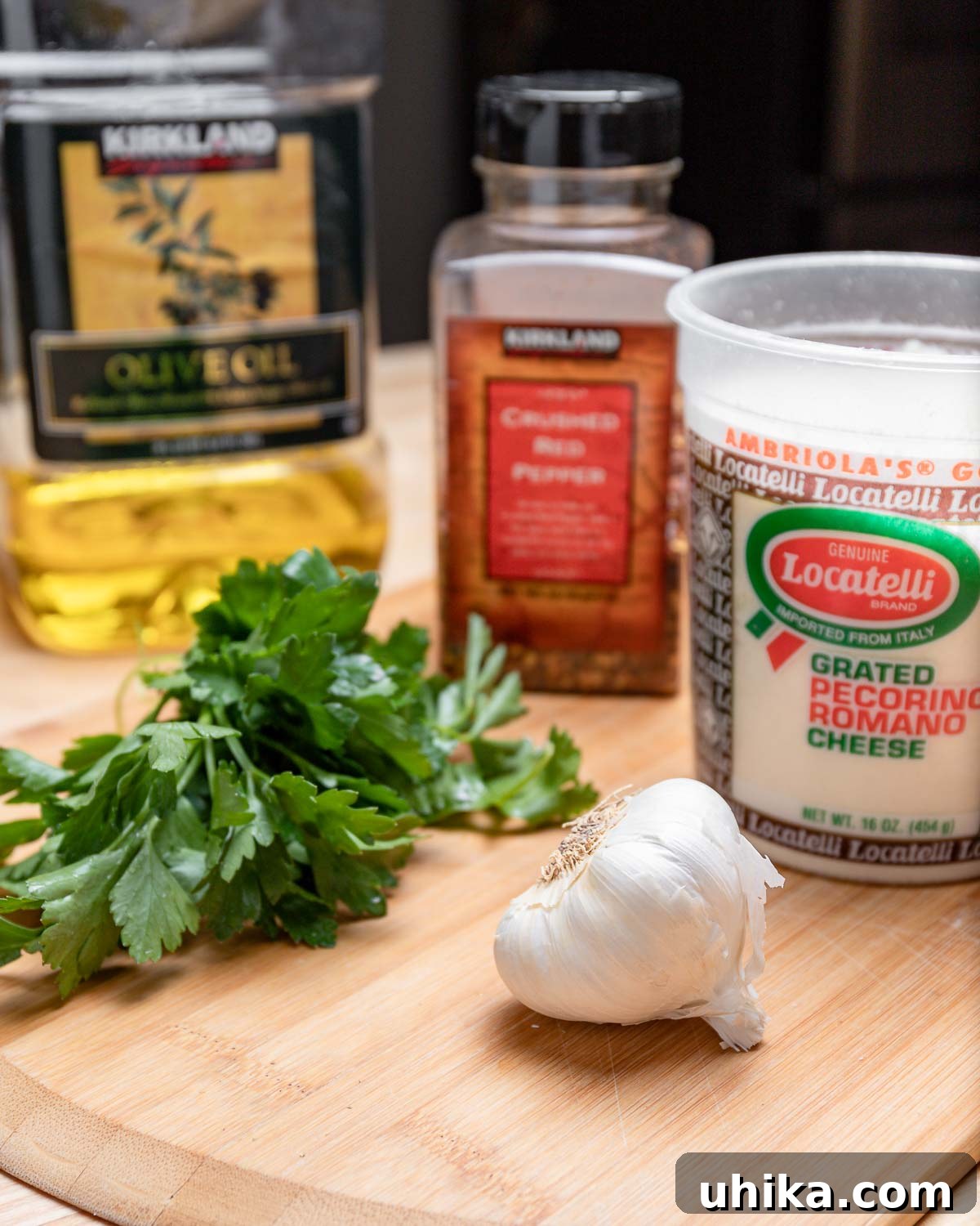 A vibrant collage displays the essential ingredients for garlic knots: rich olive oil, fresh green parsley, fiery chili flakes, grated Pecorino Romano cheese, and abundant garlic cloves.