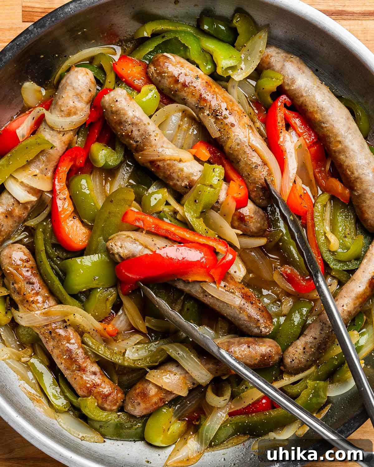 Quick 5 Ingredient Sausage and Peppers 2 Overhead shot of Italian sausage and peppers in pan with tongs.