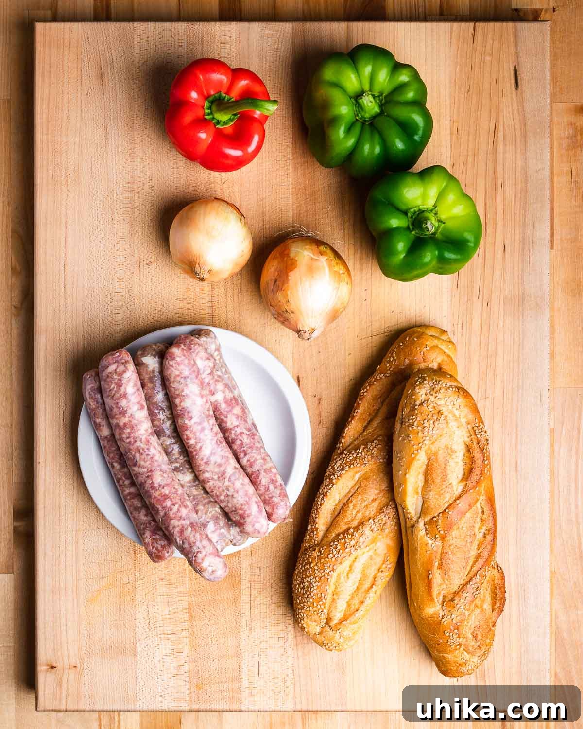 Quick 5 Ingredient Sausage and Peppers 4 Ingredients shown: red and green bell peppers, onions, Italian sausage links, and Italian bread.