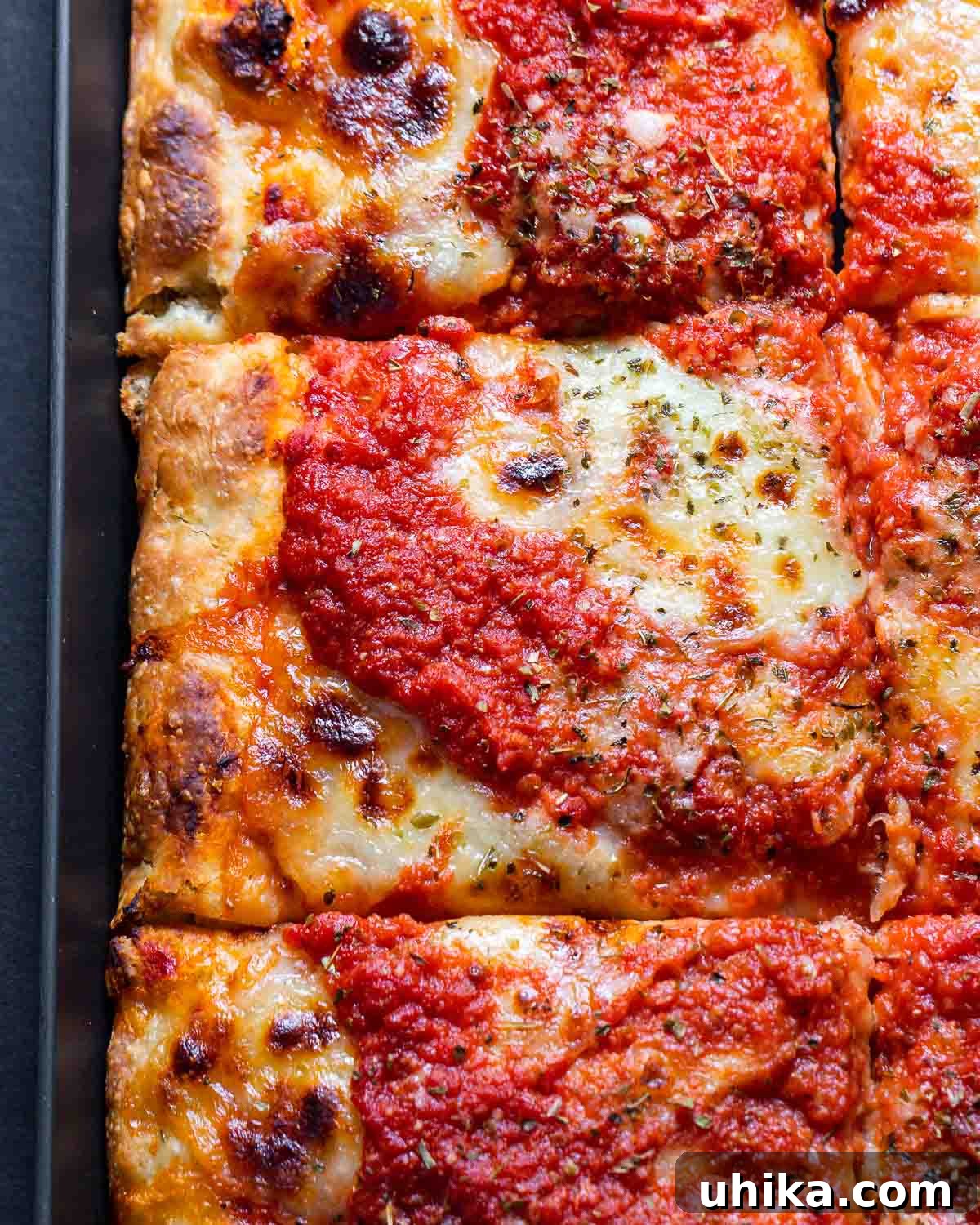 A freshly baked New York Sicilian pizza, perfectly golden and bubbly, resting in its rectangular pan.