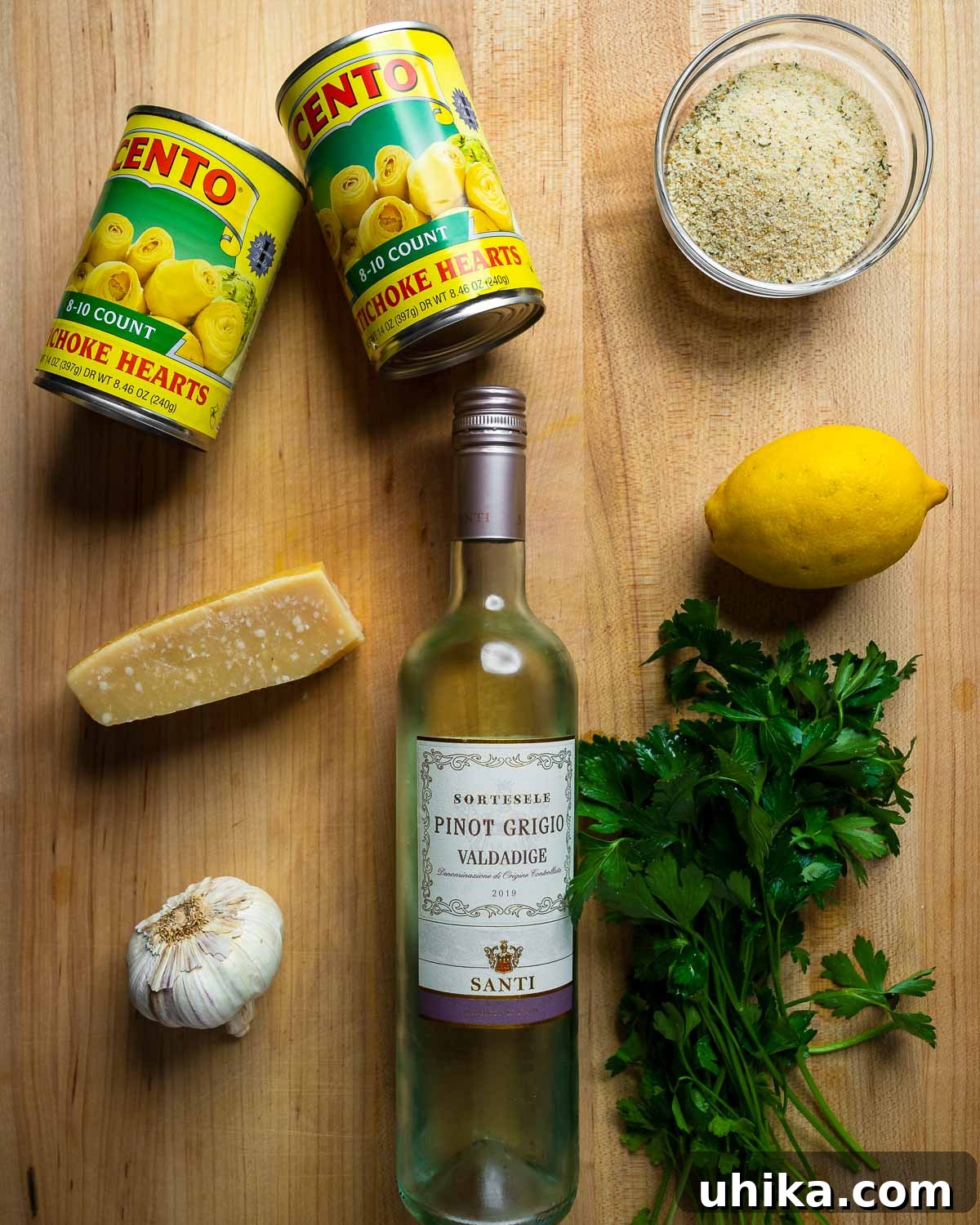 Oven-Roasted Artichoke Hearts with Garlic-Herb Breadcrumb Crust 3 Ingredients shown: canned artichoke hearts, breadcrumbs, parmesan block, lemon, wine, garlic, and parsley.