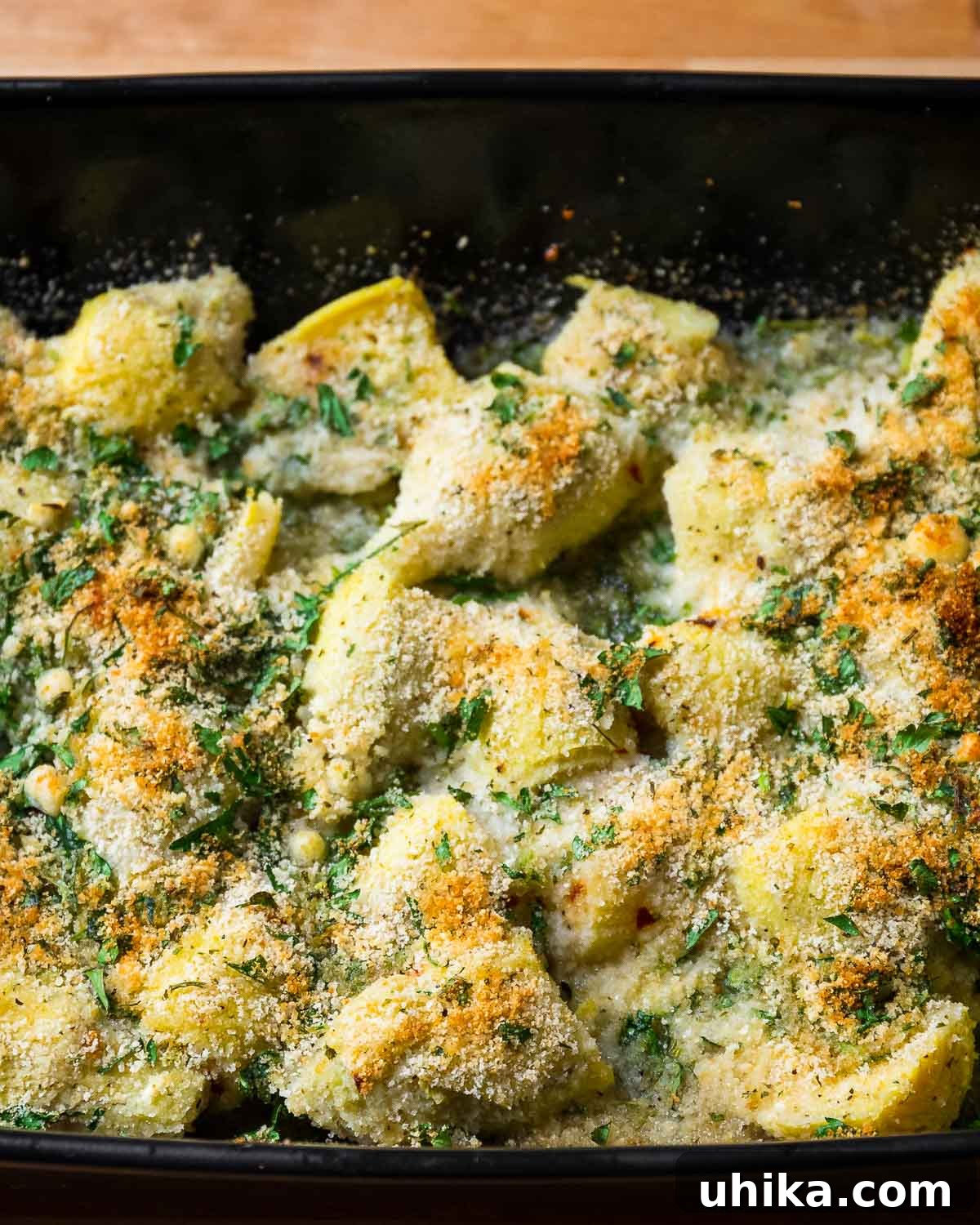 Oven-Roasted Artichoke Hearts with Garlic-Herb Breadcrumb Crust 7 Baked artichoke hearts in black dish.