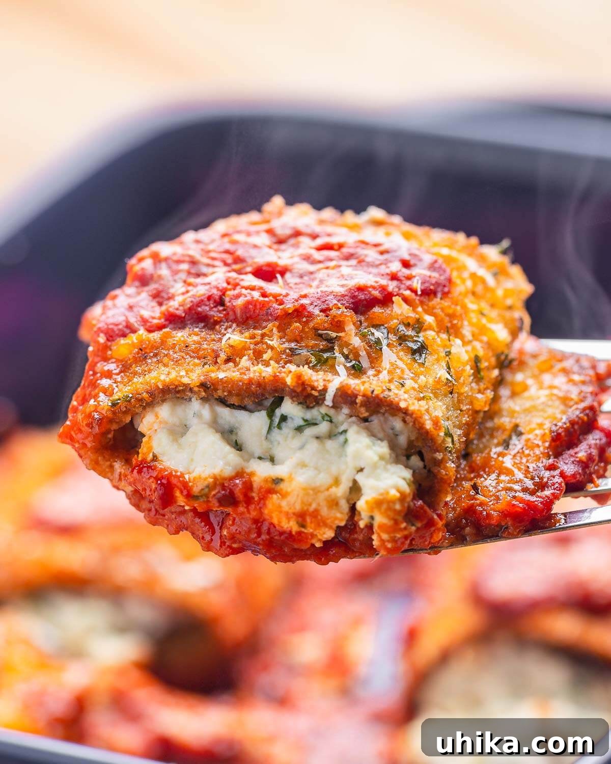 Spatula holding one piece of eggplant rollatini with steam showing.