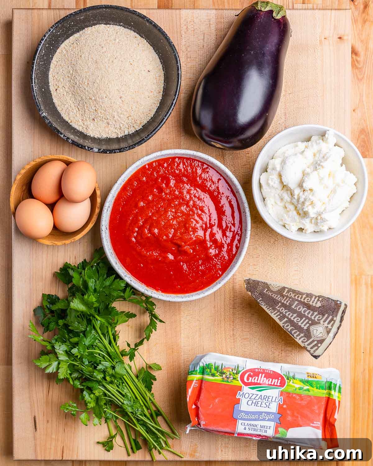 Ingredients shown: breadcrumbs, eggplant, eggs, marinara sauce, ricotta, parsley, Pecorino Romano, and mozzarella.