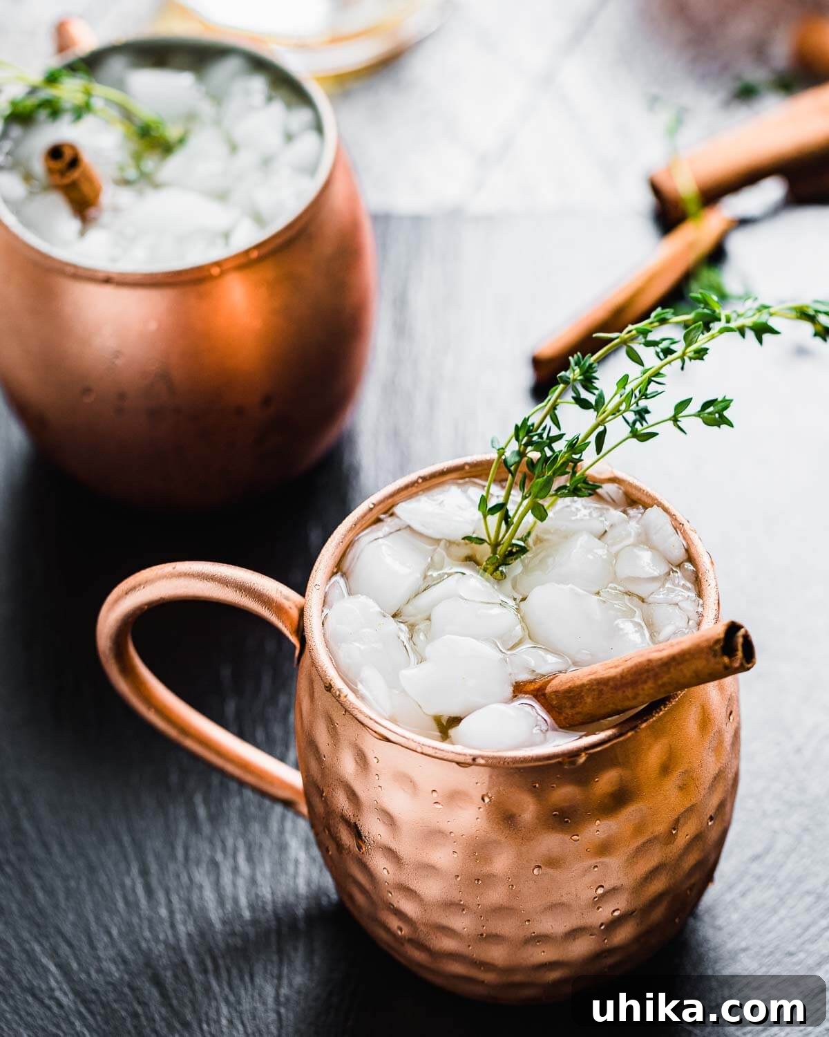 Spiced Pumpkin Harvest Mule 2 A frosty Pumpkin Spiced Mule cocktail served in a copper mug, garnished with a large cinnamon stick and a sprig of fresh thyme, set against a warm autumn backdrop.