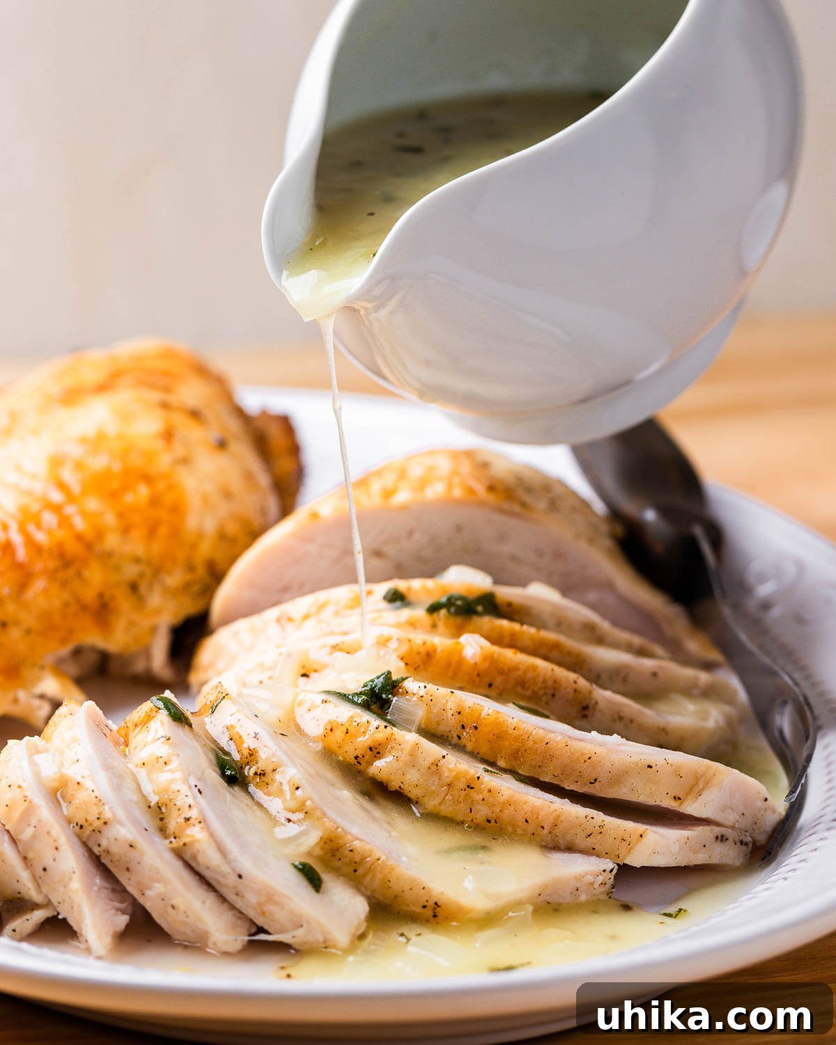 Foolproof Turkey Gravy 2 Rich turkey gravy being elegantly poured over a platter of carved, golden-brown turkey slices.