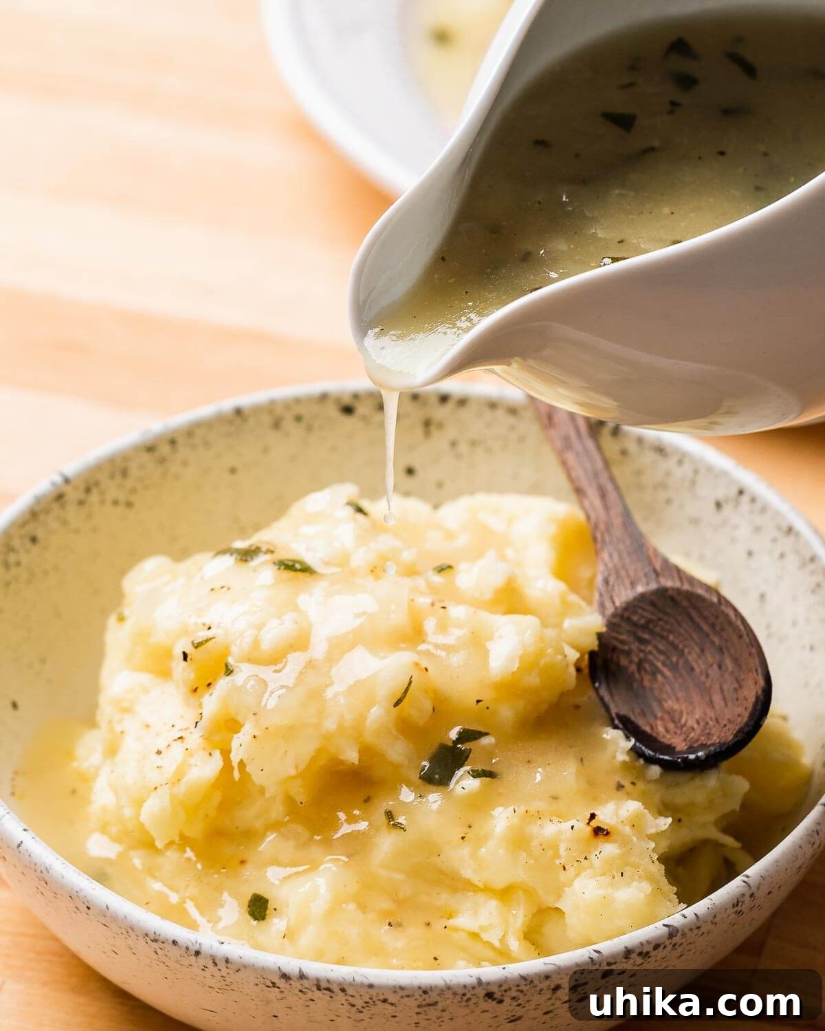 Creamy Roasted Garlic Mashed Potatoes 9 Rich brown gravy generously poured over a serving of creamy roasted garlic mashed potatoes in a pristine white bowl.