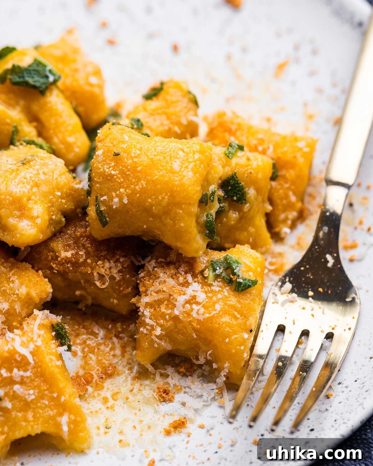 White plate with gold fork and butternut squash gnocchi.