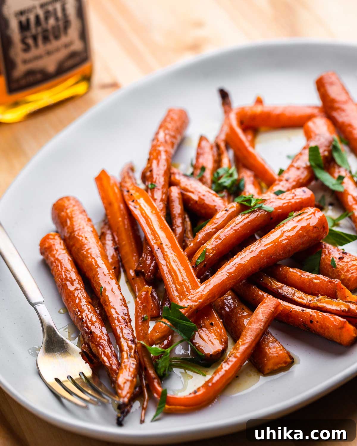 Candied Maple Carrots 2 Large plate with maple roasted carrots and bottle of maple syrup.