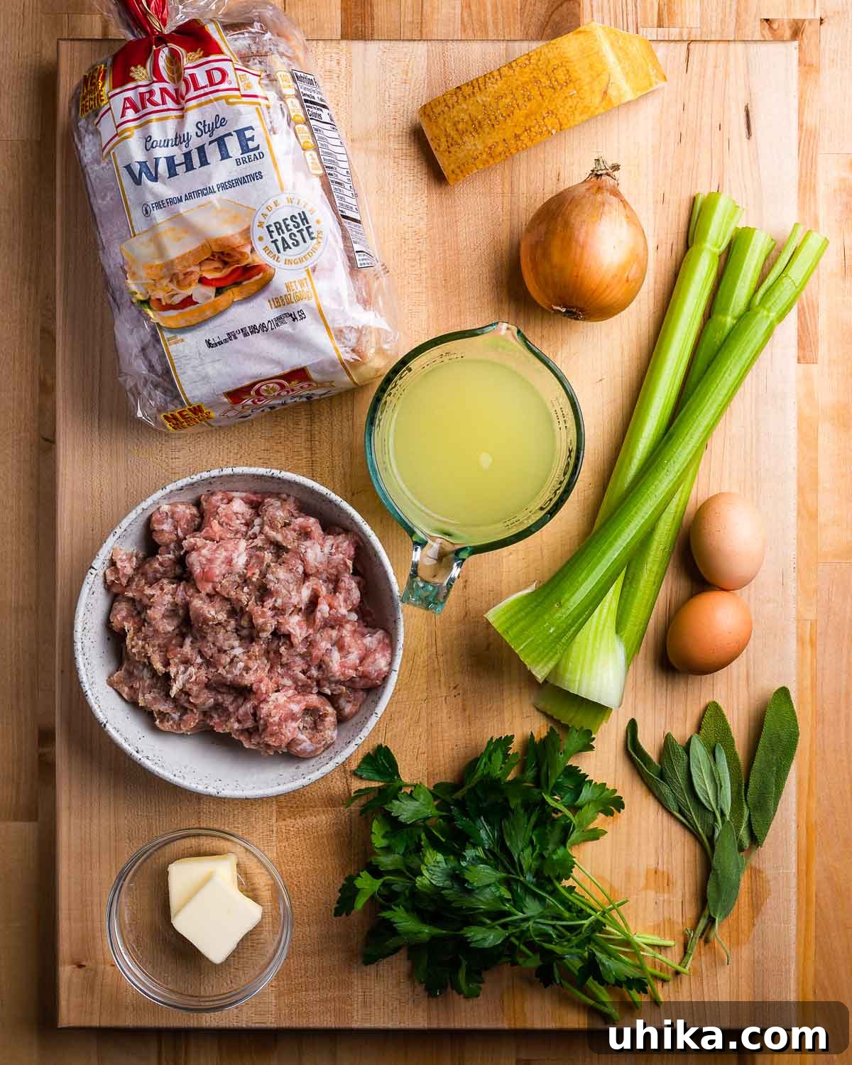 Parmesan-Infused Italian Sausage Stuffing 3 Ingredients shown: white bread, parmesan, onion, celery, chicken stock, sausage, butter, eggs, and herbs.
