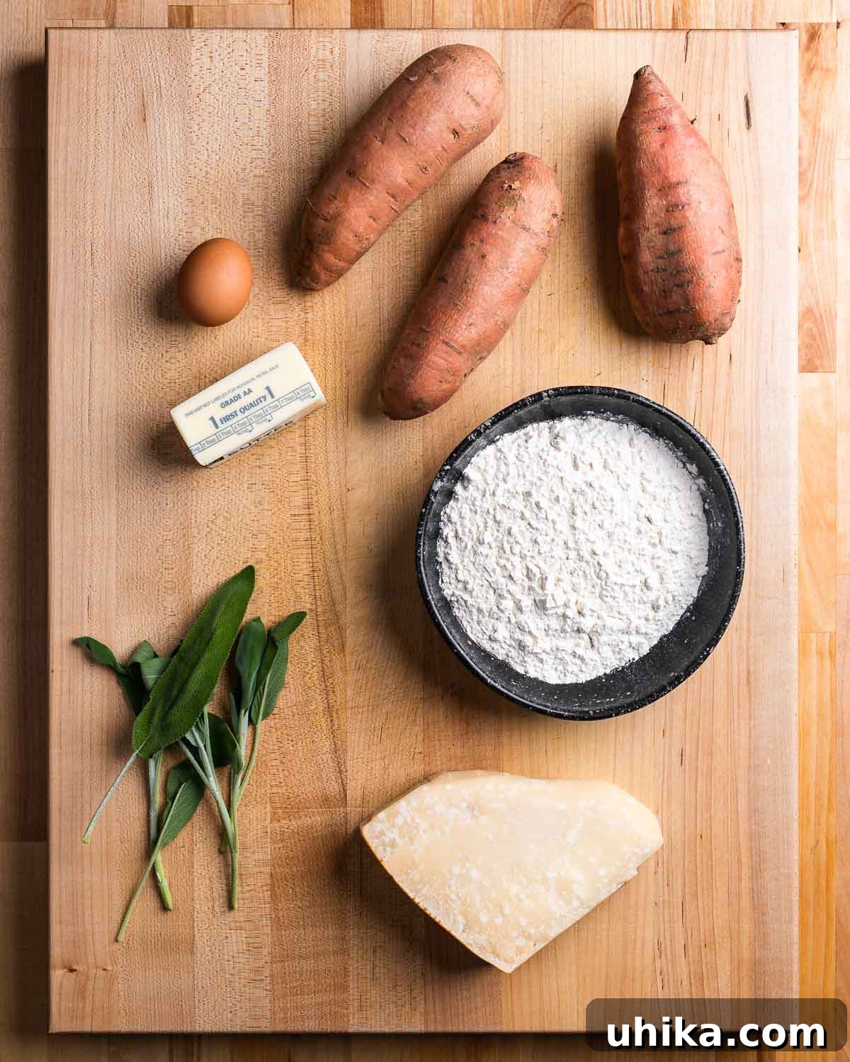 Maple Brown Butter Sweet Potato Gnocchi 3 A selection of ingredients for sweet potato gnocchi, including sweet potatoes, egg, butter, flour, sage, and parmesan cheese.