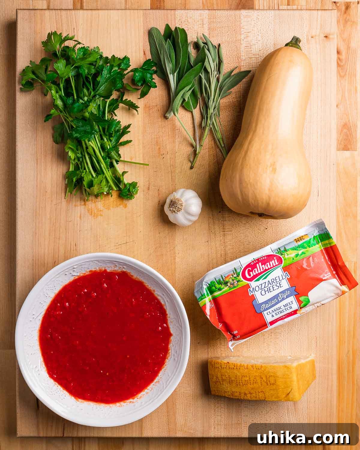 Autumn Squash Parmesan Bake 3 Ingredients shown: parsley, sage, butternut squash, garlic, sauce, mozzarella, and parmesan cheese.