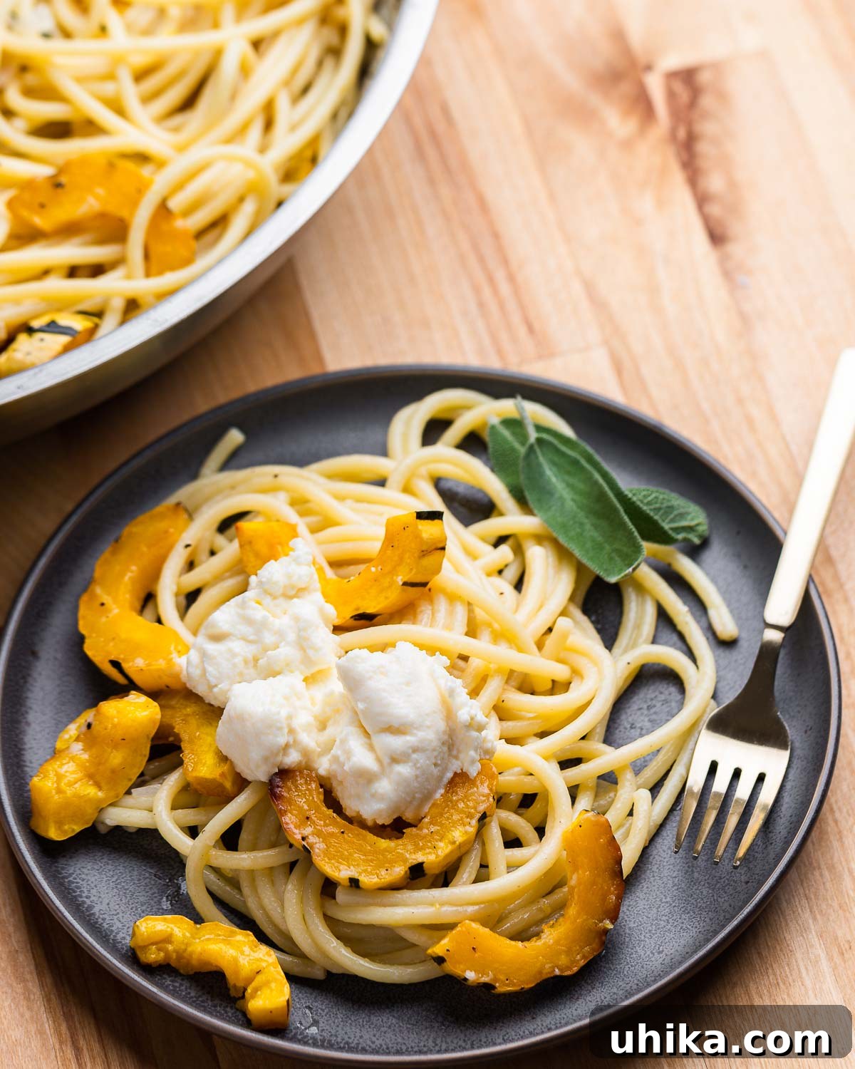 Grey plate with delicata squash pasta and dollop of ricotta on top.