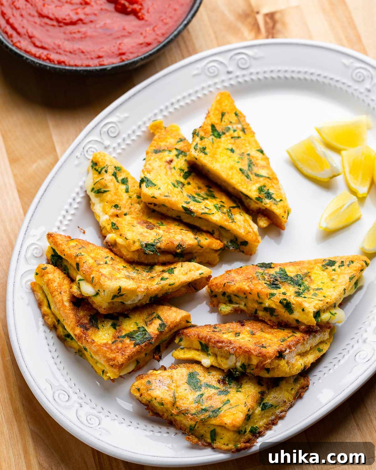 Golden Fried Mozzarella Toast 2 Golden-fried Mozzarella en Carrozza triangles arranged on a white plate with fresh lemon wedges.