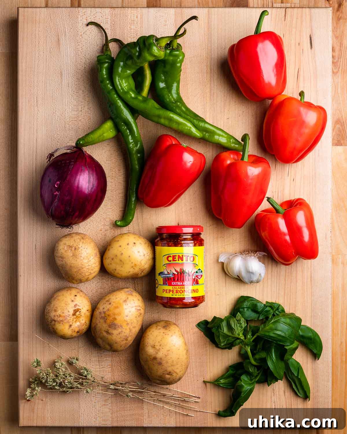 Calabrian Potatoes and Peppers 3 A vibrant display of fresh ingredients for Calabrian-style potatoes and peppers, including Long Hot peppers, red bell peppers, red onion, garlic, basil, Sicilian oregano, and Calabrian chili paste.