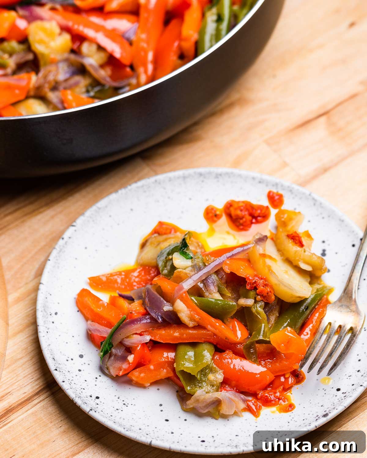 Calabrian Potatoes and Peppers 7 A perfectly portioned serving of spicy Calabrian-style potatoes and peppers on a white plate, garnished with fresh basil.