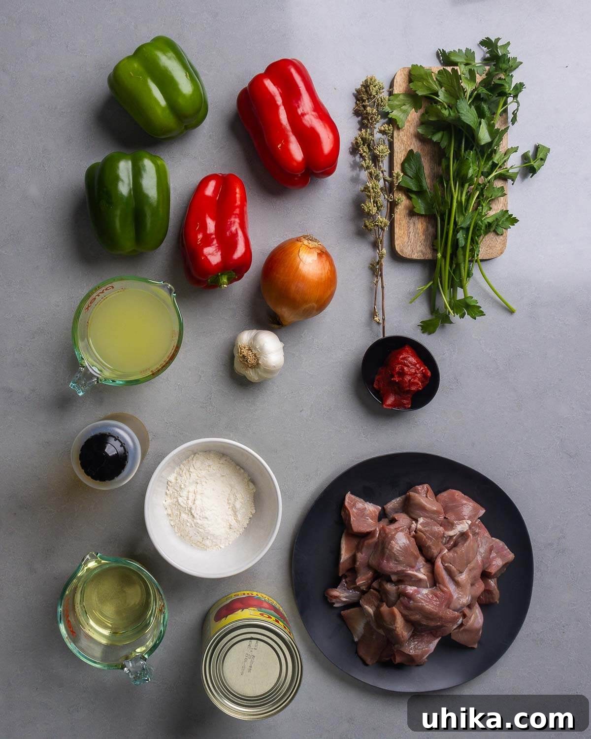 Timeless Veal and Peppers 4 A flat lay of all fresh ingredients for Veal and Peppers recipe, including cubed veal, bell peppers, onions, garlic, tomatoes, and herbs.