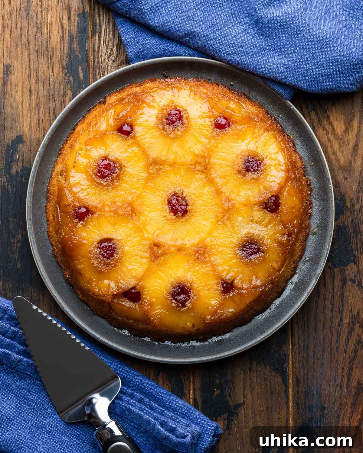 Golden Pineapple Delight 2 A slice of Pineapple Upside Down Cake on a grey plate, with a cake spatula nearby.