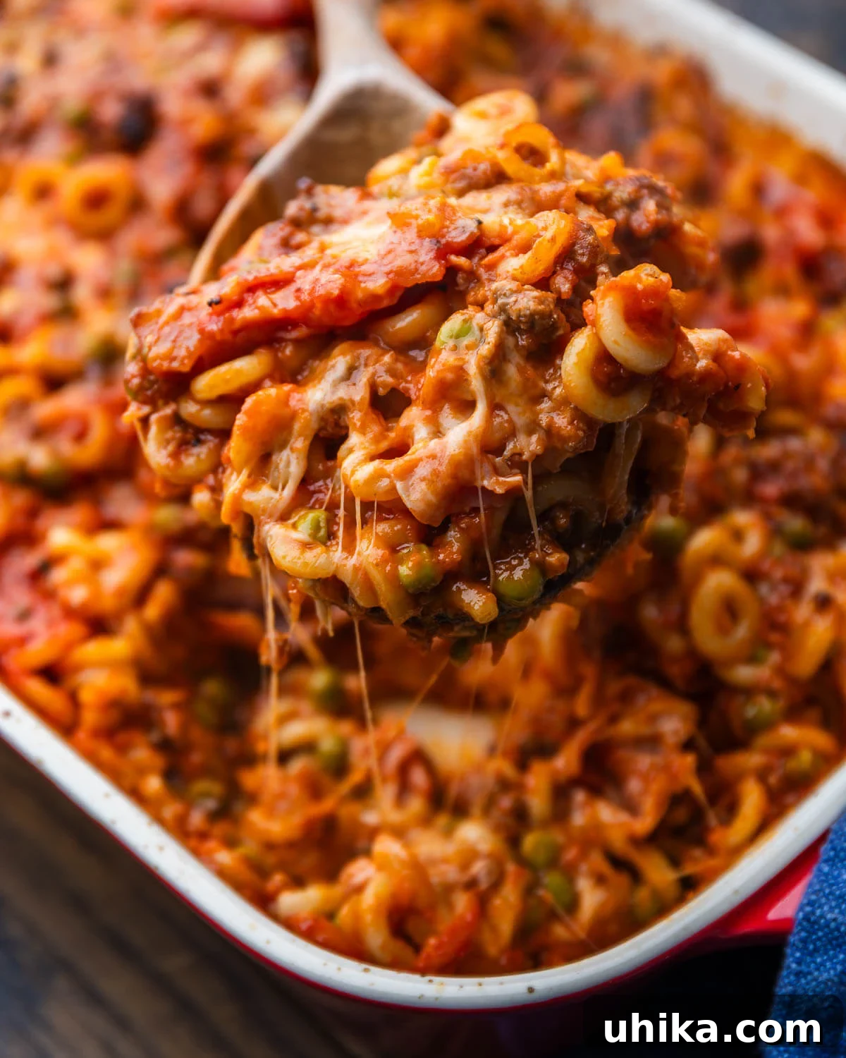 Baked Anelletti from Sicily 2 Large portion of Anelletti al Forno scooped onto a wooden spoon, showcasing the ring-shaped pasta, rich meat sauce, and melted cheese.