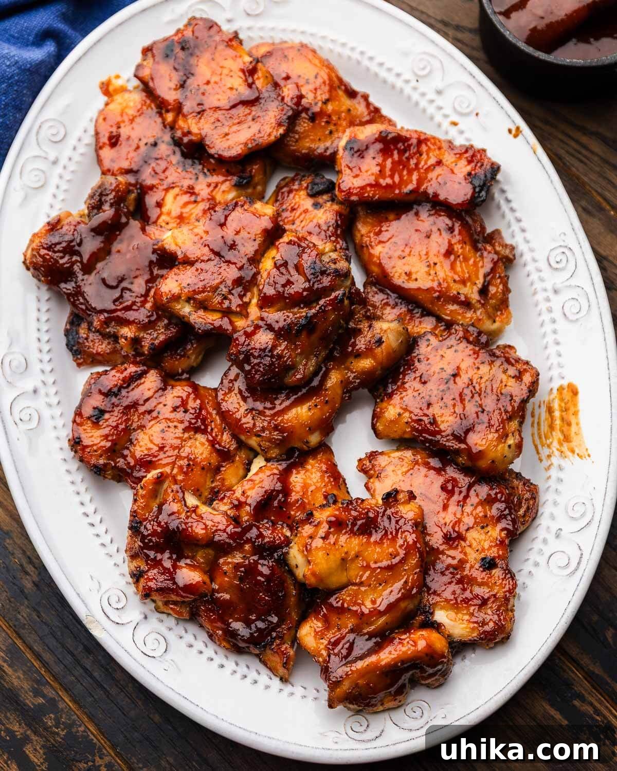 Perfectly Glazed Oven BBQ Chicken Thighs 2 A platter brimming with perfectly caramelized oven baked barbecue chicken thighs, garnished with fresh herbs.