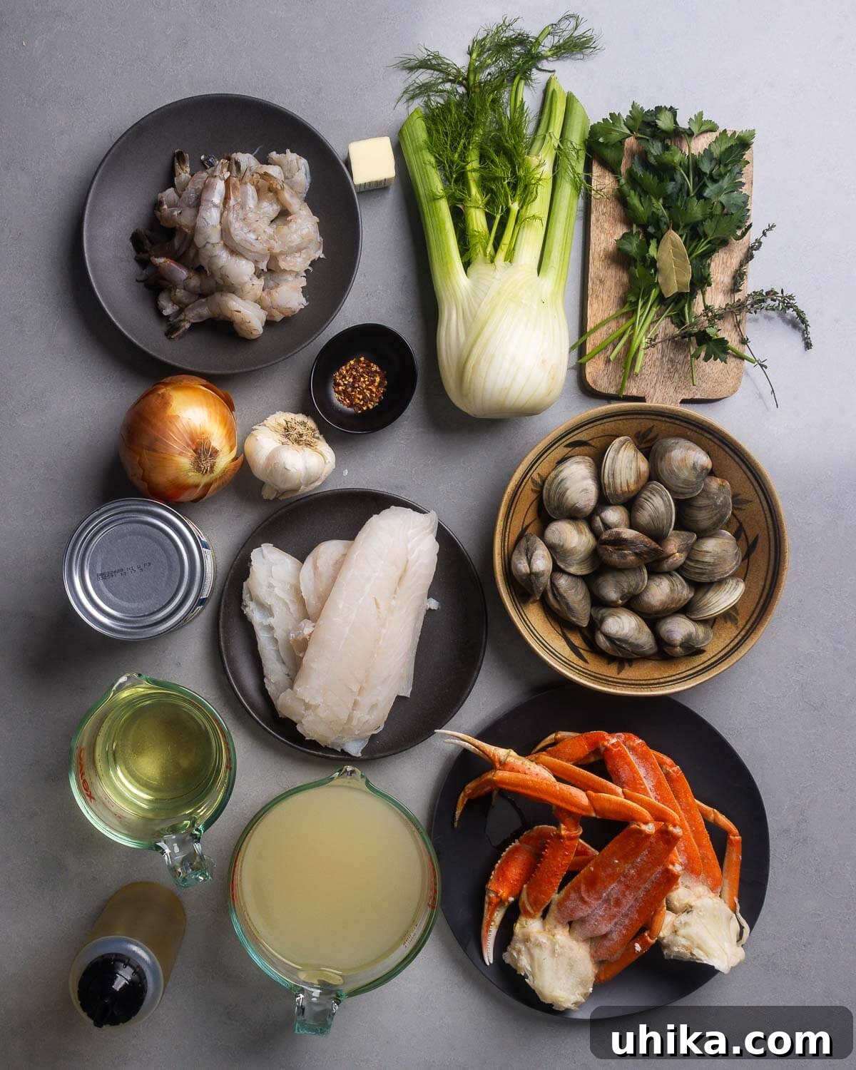 Cioppino A Robust Maritime Feast 4 A vibrant flat lay of all the fresh ingredients for Cioppino: shrimp, crushed red pepper flakes, fresh fennel, parsley, bay leaves, thyme, onion, garlic, canned tomatoes, cod fillets, fresh clams, dry white wine, olive oil, clam juice, and snow crab legs.