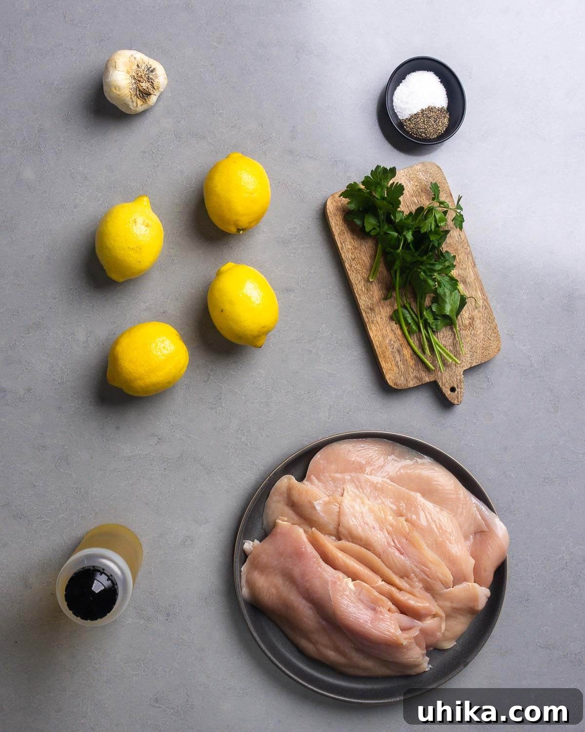 Effortlessly Delicious Marinated Grilled Chicken 4 Ingredients shown: garlic, salt, pepper, lemons, parsley, olive oil, and chicken cutlets.
