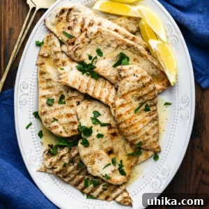 Effortlessly Delicious Marinated Grilled Chicken 8 Platter of marinated grilled chicken topped with parsley and served with lemon wedges.