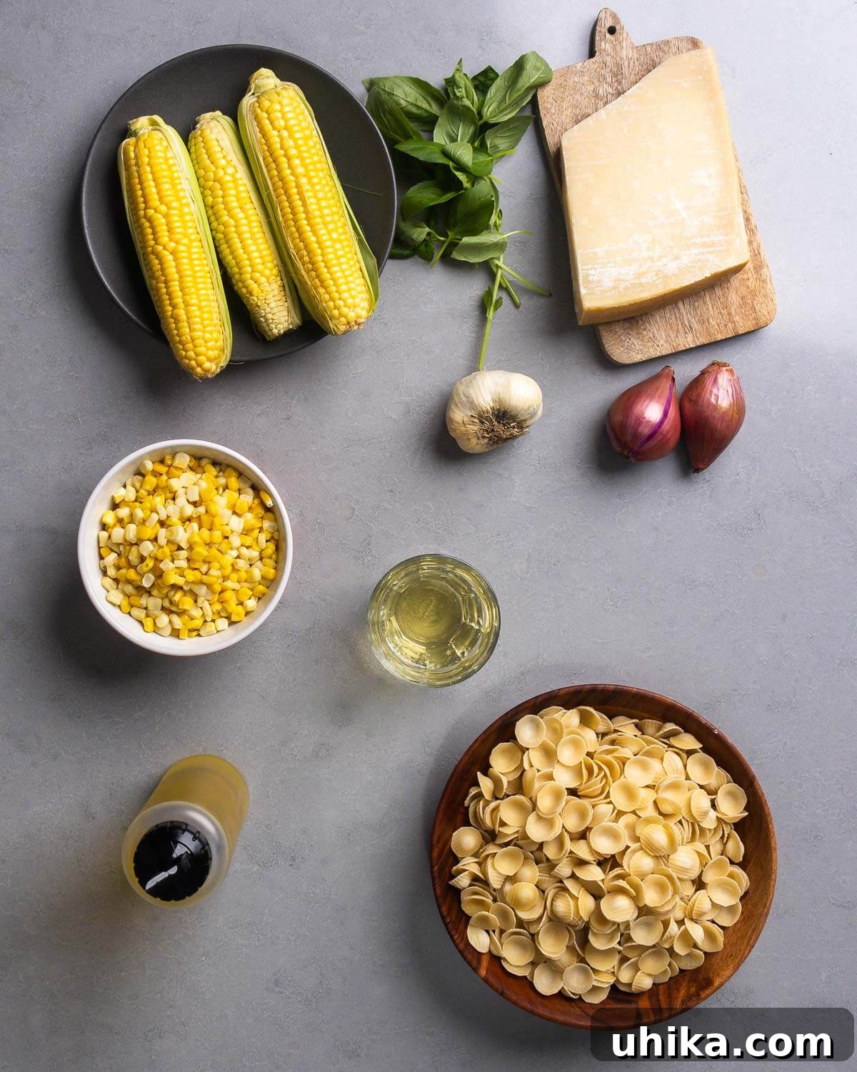 Sunshine in a Bowl: Easy Creamy Corn Pasta 4 Ingredients shown: corn cobs and frozen kernels, basil, parmigiano reggiano, garlic, shallots, white wine, olive oil, and orecchiette pasta.