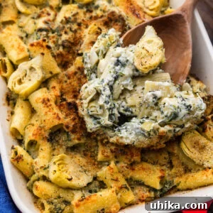 Creamy Baked Spinach and Artichoke Pasta Casserole 6 Large spoon scooping baked artichoke pasta.