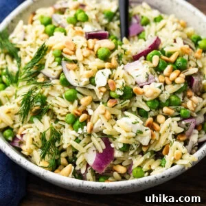 Lemon Herb Orzo Salad — Fresh Summer Side Dish 6 White bowl with lemon herb orzo salad topped with toasted pine nuts.