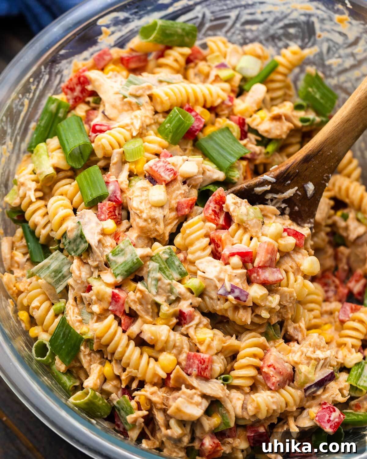 Sweet and Tangy BBQ Chicken Pasta Salad Recipe 2 Spoon scooping barbecue chicken pasta salad out of bowl.