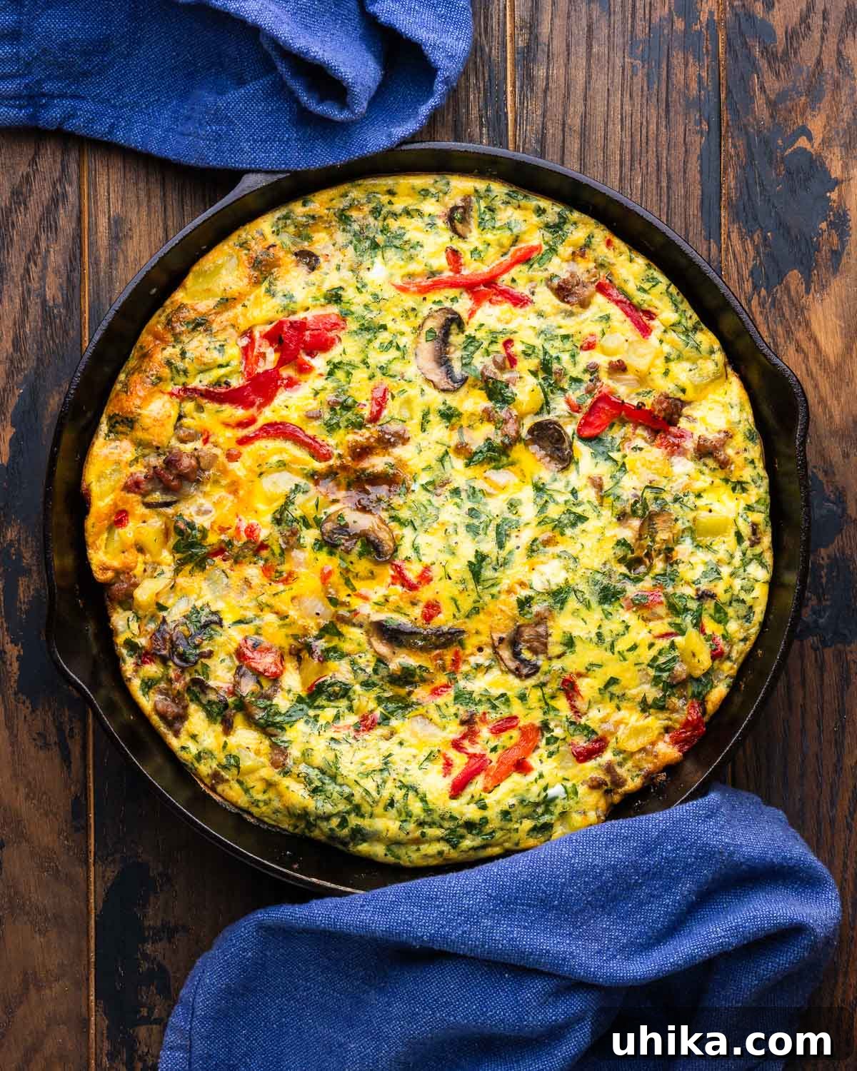 Sausage and Mushroom Frittata Recipe for Busy Weeknights 2 Large cast iron pan with sausage mushroom frittata on wood table.